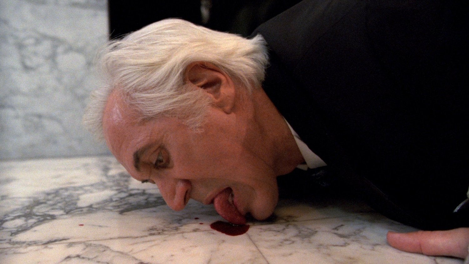A man licks blood from a floor