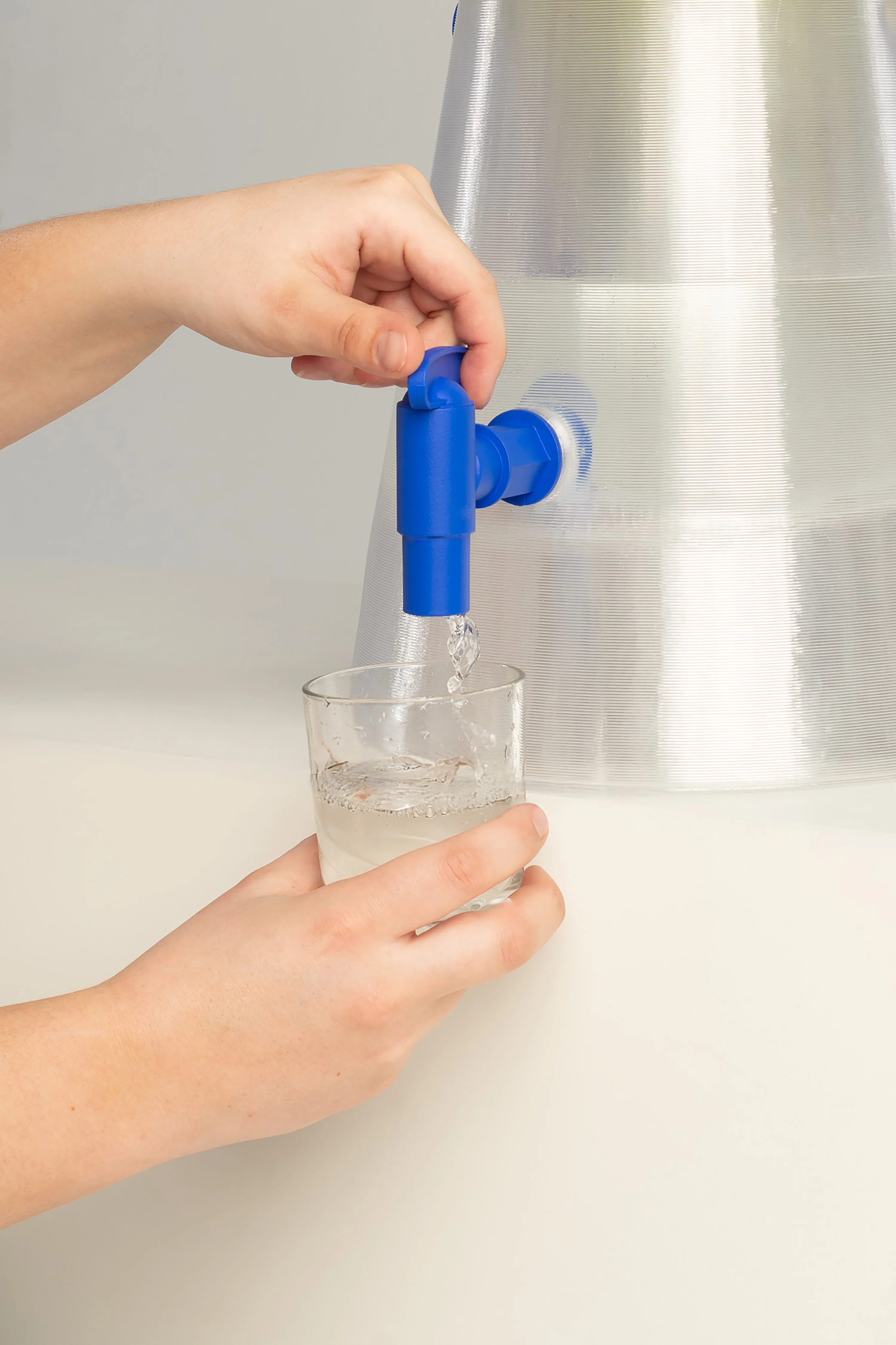 ένα άτομο ρίχνει ένα ποτήρι νερό από την κανάτα