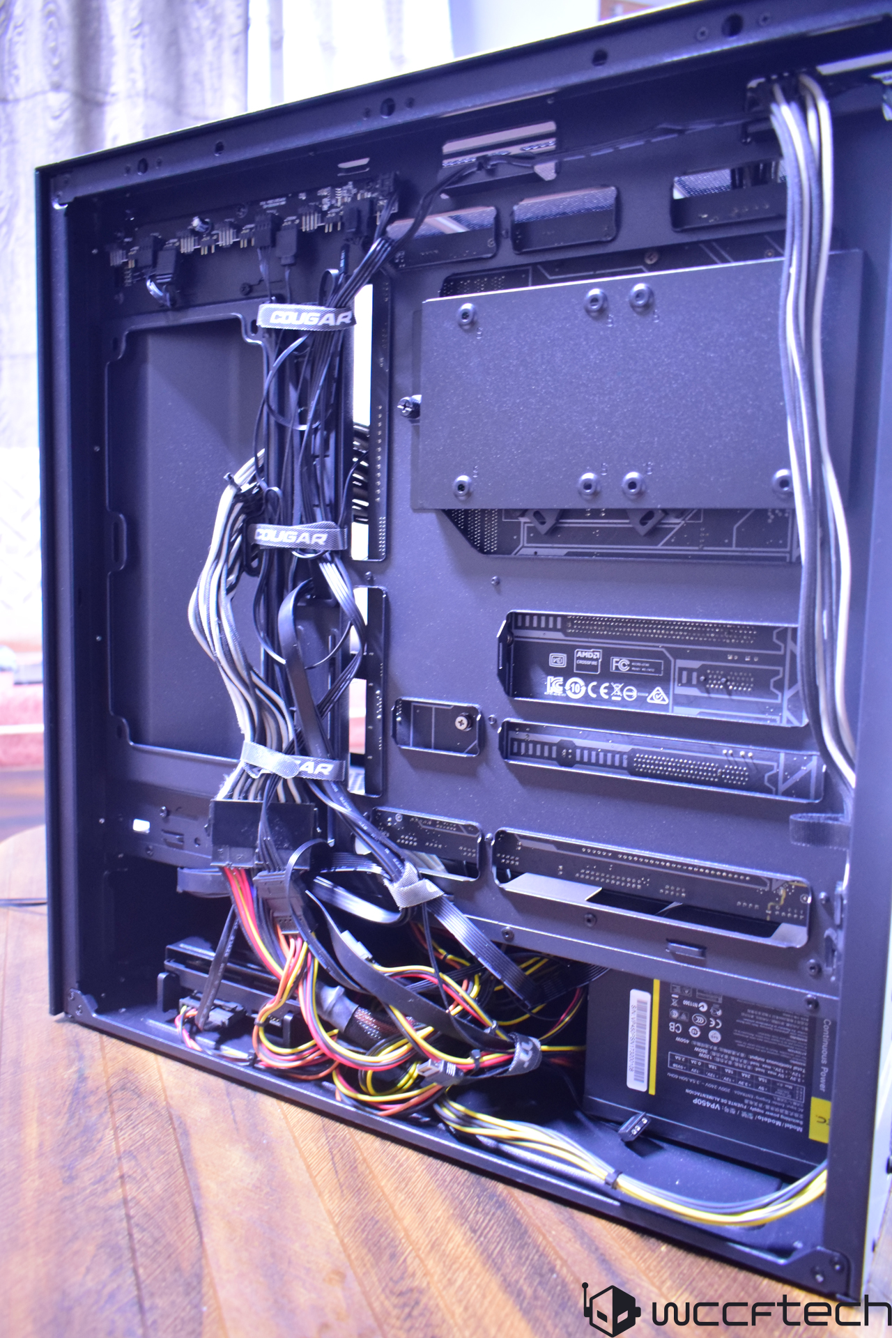 Το εσωτερικό ενός αποσυναρμολογημένου επιτραπέζιου υπολογιστή με εμφανή λουριά καλωδίων επώνυμων Cougar και διαχείριση καλωδίων.