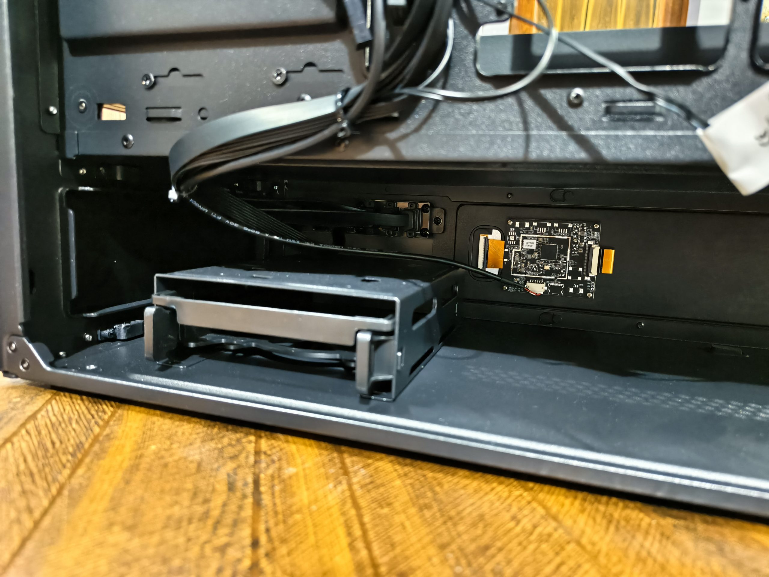 Το εσωτερικό μιας θήκης υπολογιστή χωρίς επωνυμία που δείχνει μια εγκατεστημένη μικρή πλακέτα κυκλώματος, καλώδια και κενές θέσεις μονάδας δίσκου.