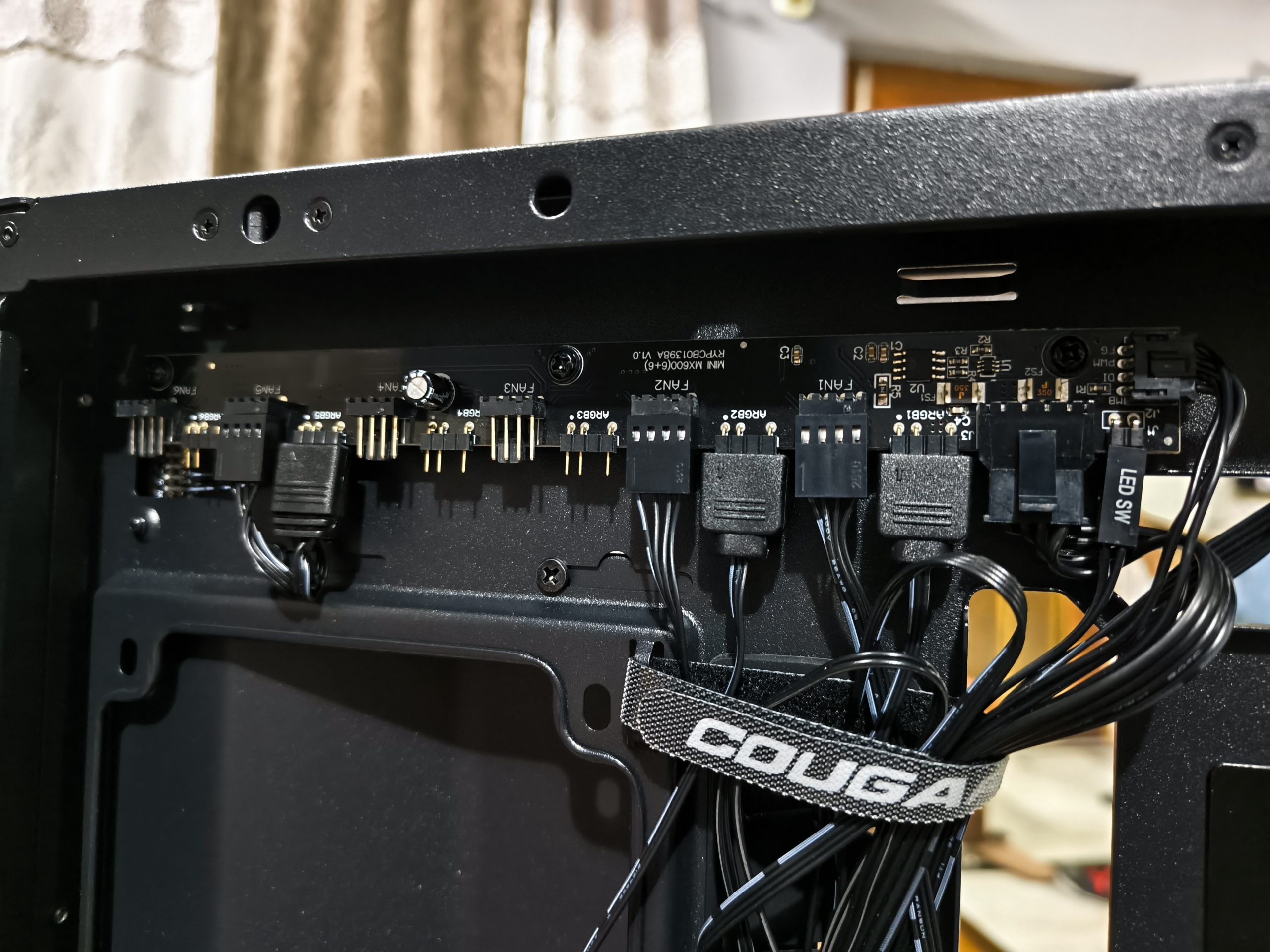 Εσωτερική θήκη υπολογιστή με την επωνυμία Cougar που δείχνει μια πλακέτα ελεγκτή ανεμιστήρα με συνδεδεμένα καλώδια με την ένδειξη «LED SW».