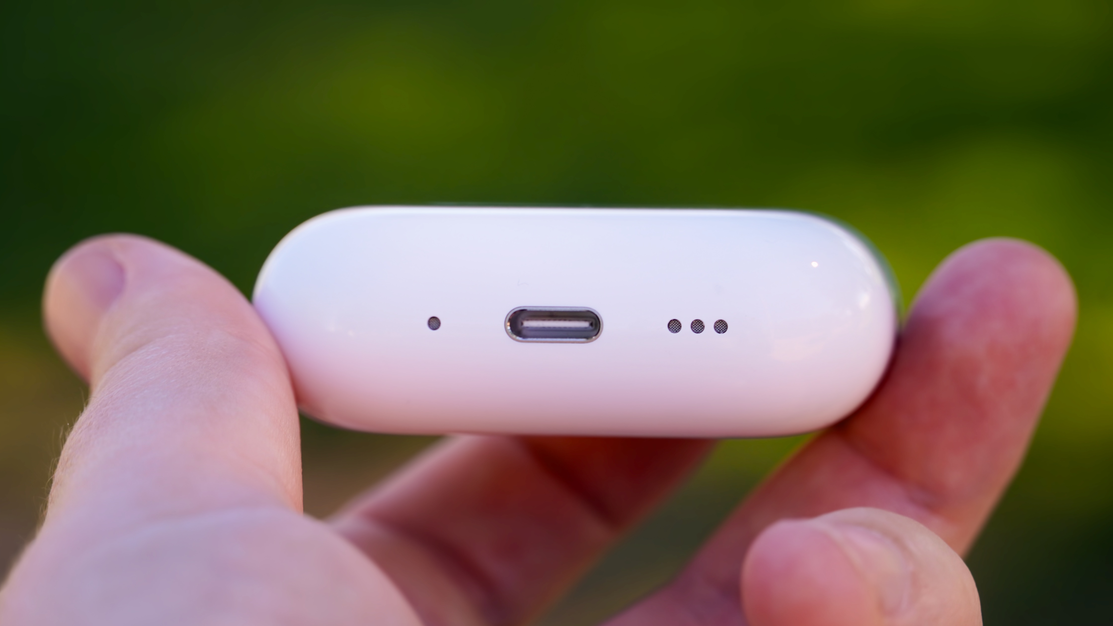 The AirPods Pro 3 with their charging case at a park.