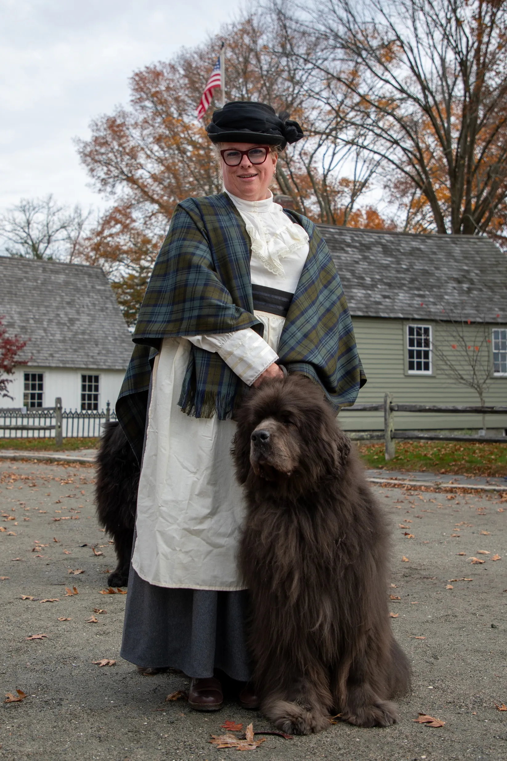 μια γυναίκα με ρούχα του 19ου αιώνα που στέκεται με ένα μεγάλο σκυλί