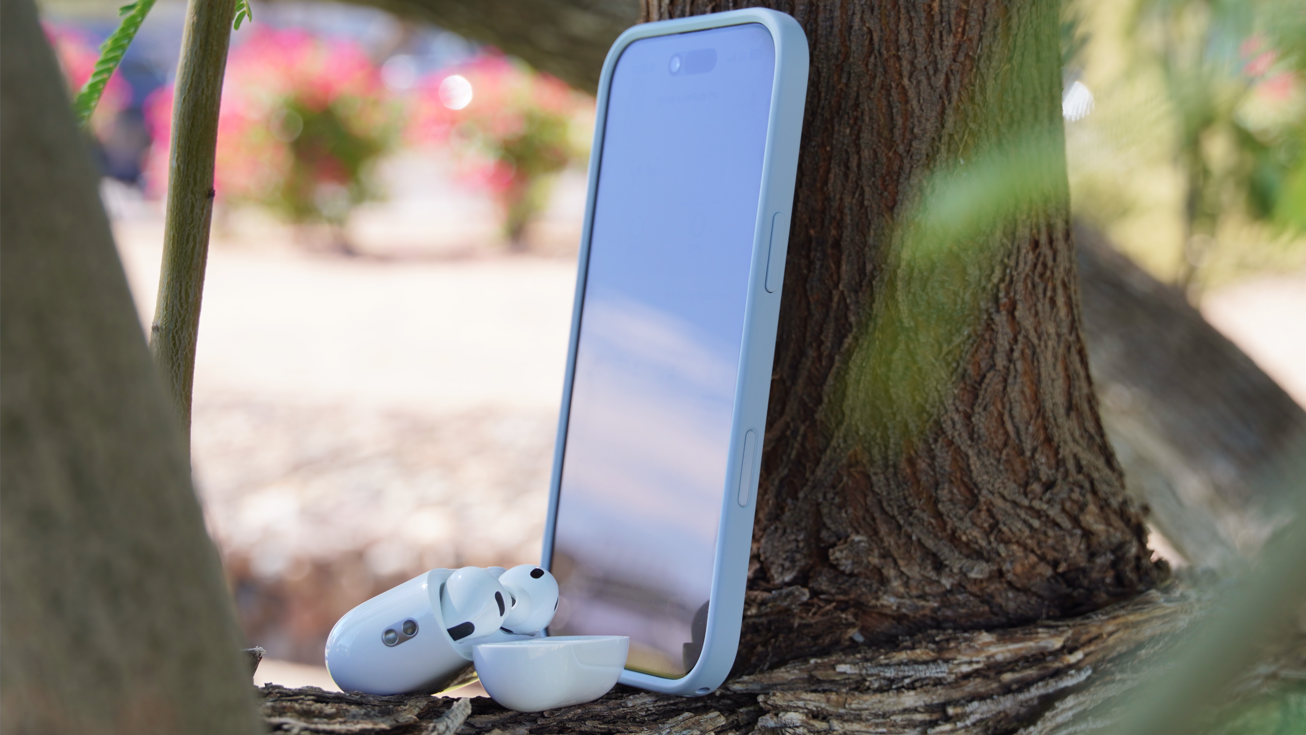 The AirPods Pro 3 with their charging case at a park.