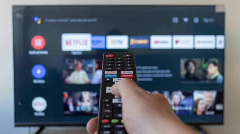 Άτομο που κρατά την απομακρυσμένη πλοήγηση στη διεπαφή Android TV στην οθόνη.