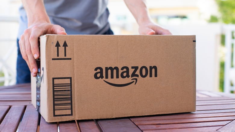 Ένα άτομο με ένα γαλάζιο πουκάμισο με τα δύο του χέρια σε ένα πακέτο Amazon