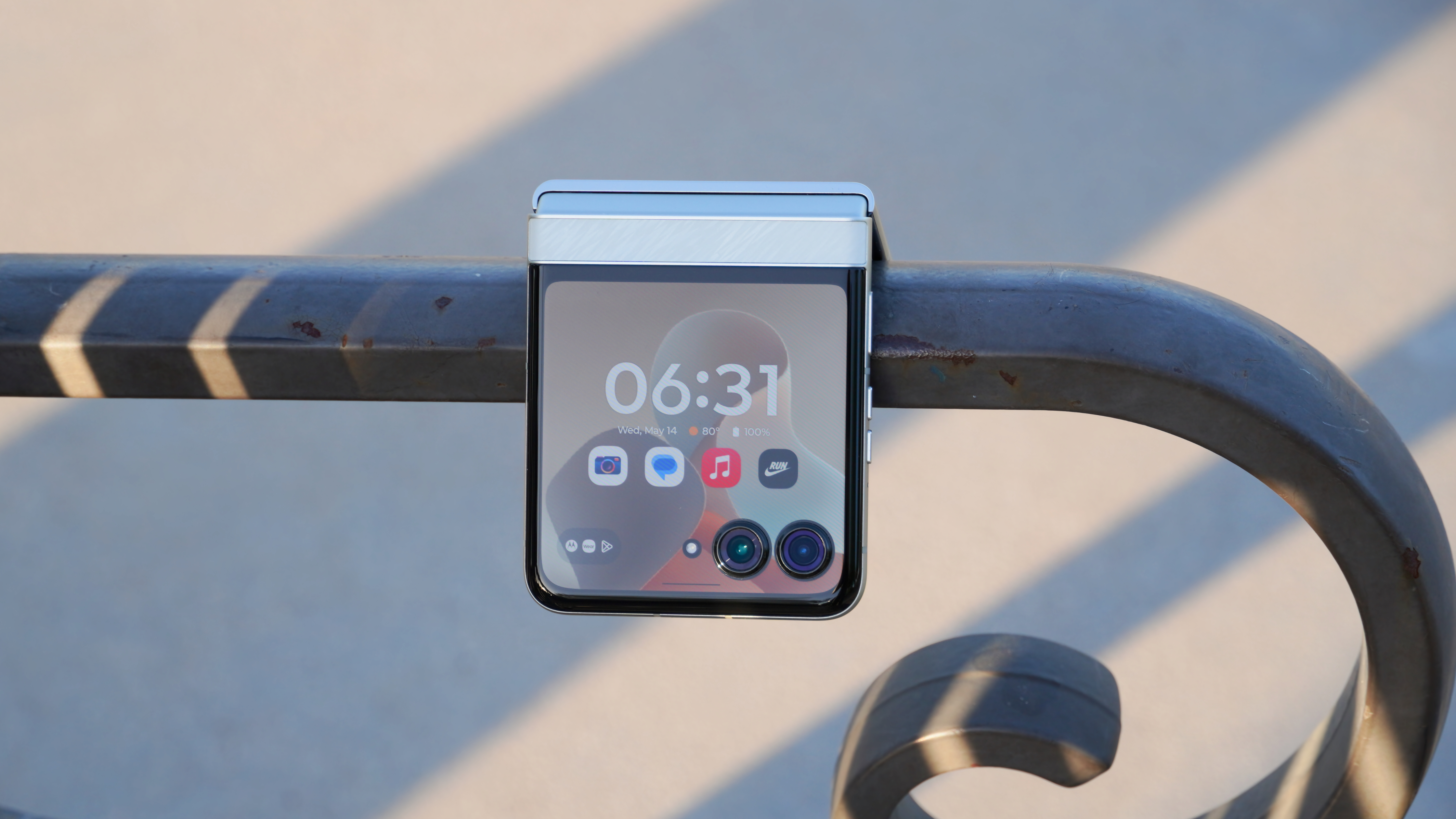 Το Motorola Razr 2025 στο Pantone Lightest Sky κρέμεται από ένα παγκάκι στο πάρκο.