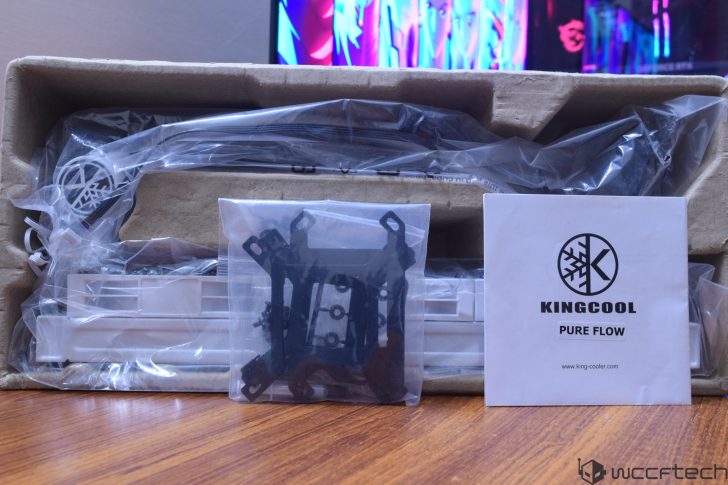 Συσκευασία του συστήματος ψύξης «PURE FLOW» KINGCOOL, που περιλαμβάνει εξαρτήματα τυλιγμένα σε πλαστικό και οδηγό εγκατάστασης.