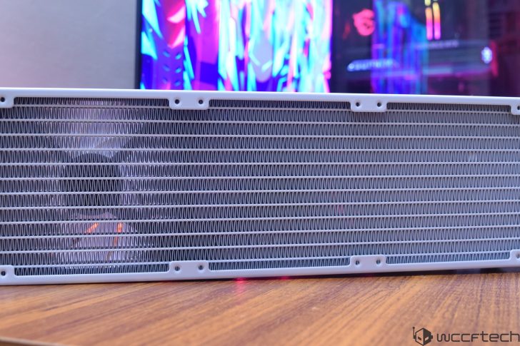 Ένα μεγάλο ψυγείο υπολογιστή χωρίς επωνυμία τοποθετείται σε μια ξύλινη επιφάνεια με μια πολύχρωμη, εκτός εστίασης ρύθμιση gaming ορατή στο φόντο.