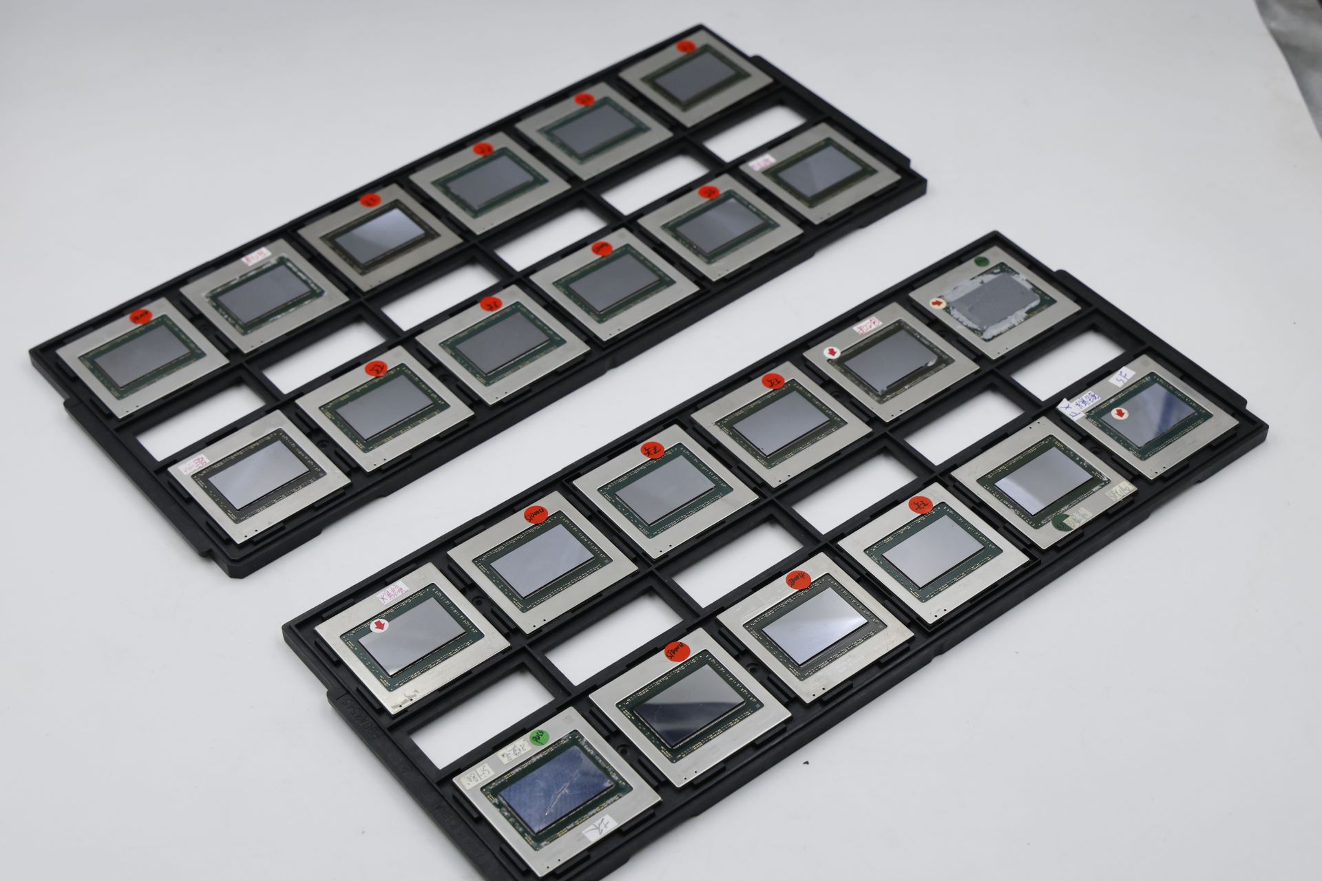 Δύο δίσκοι που περιέχουν πολλά μη επώνυμα τσιπ ημιαγωγών με ορατές ετικέτες, τακτοποιημένα σε μια λευκή επιφάνεια.