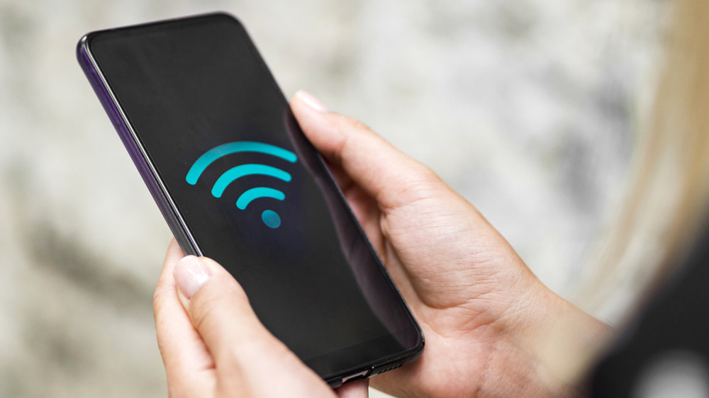 Το σύμβολο Wi-Fi που εμφανίζεται στην οθόνη ενός smartphone που κρατιέται στα χέρια ενός ατόμου.