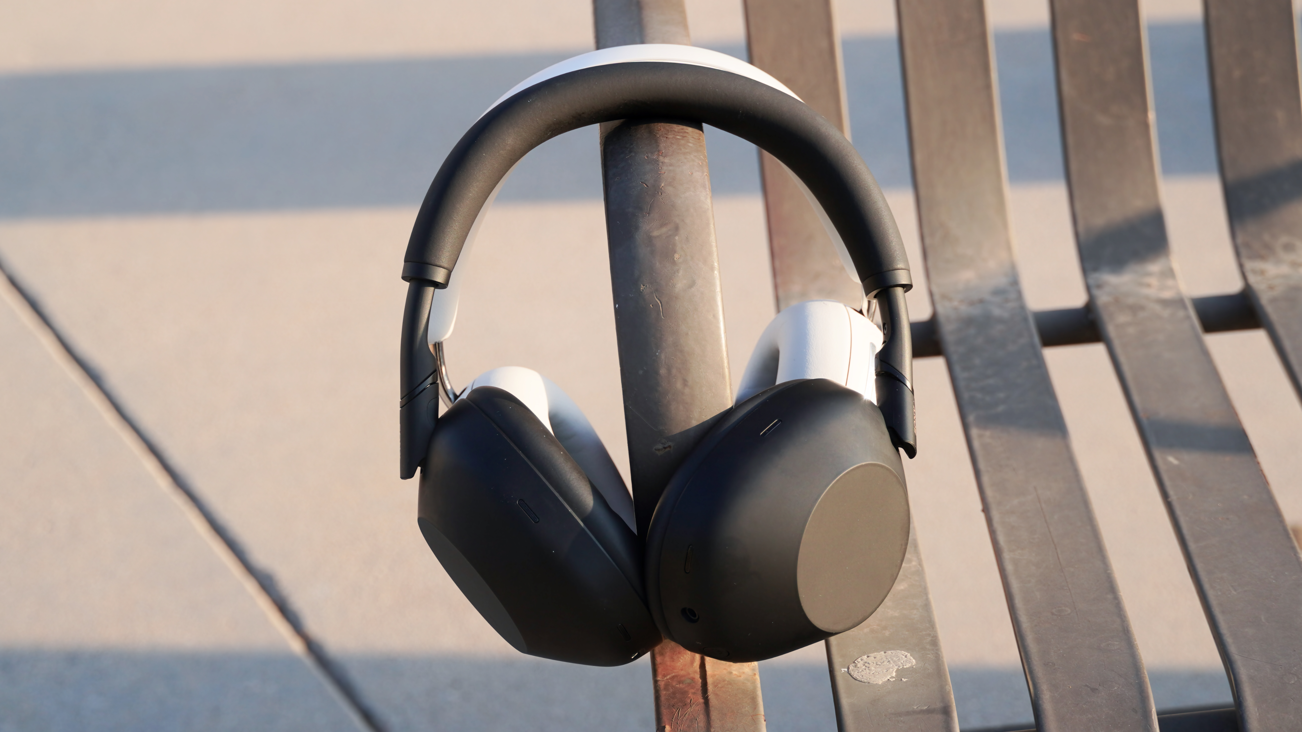 Το Sony WH-1000XM6 μπροστά στον Sonos Ace σε ένα παγκάκι στο πάρκο.