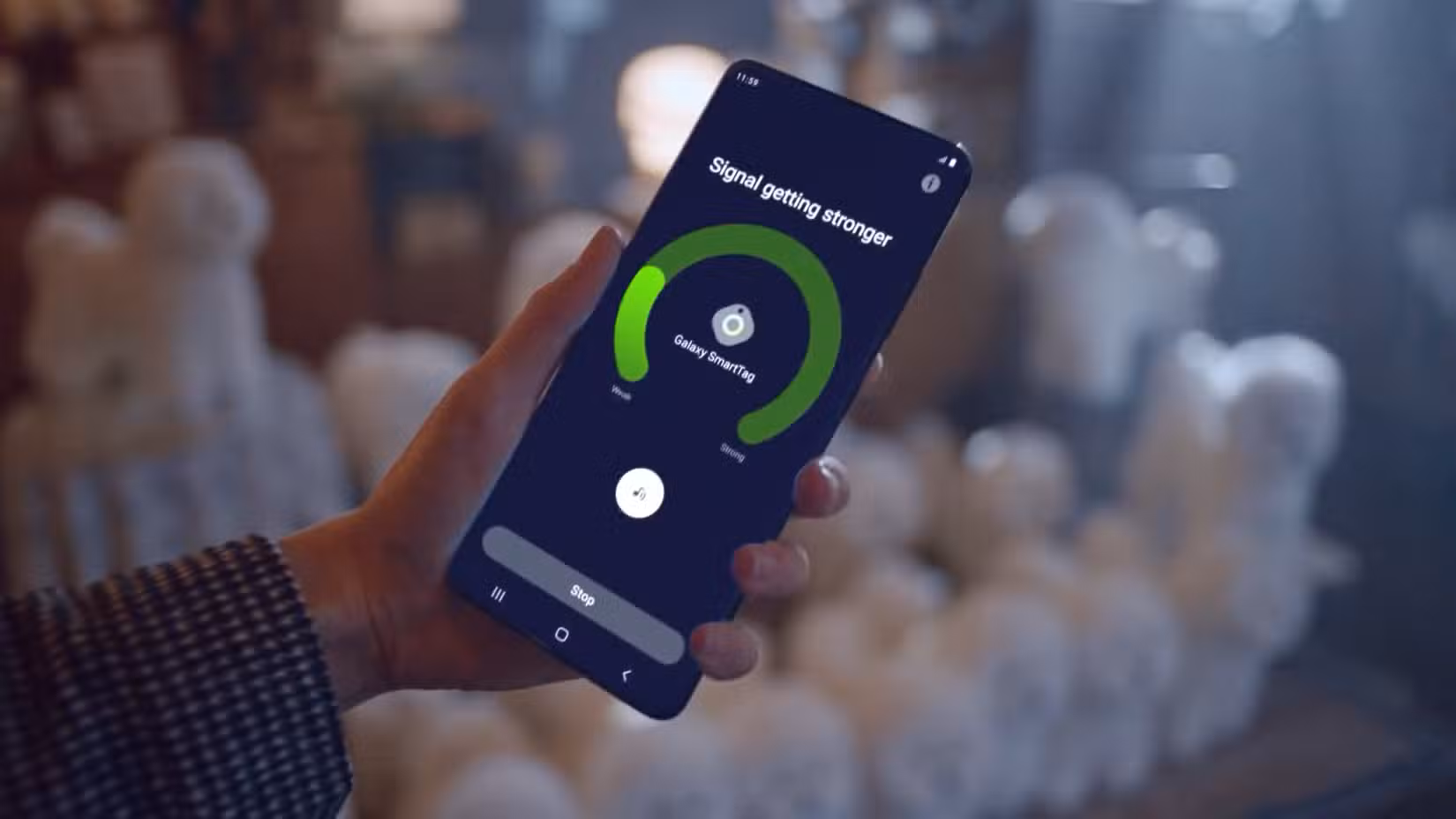 Ένα άτομο που κρατά ψηλά ένα smartphone με μια εφαρμογή που εμφανίζει την ισχύ του σήματος για το Galaxy SmartTag