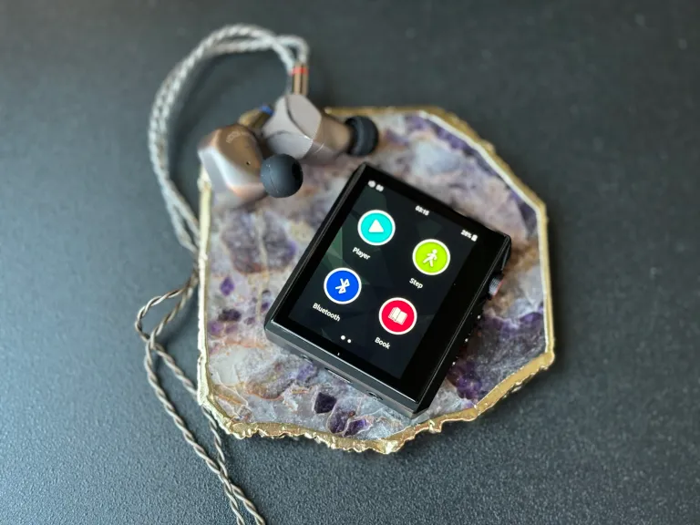Small black square Hidizs AP80 Pro-X DAP sitting on a marble coaster with titanium IEMs