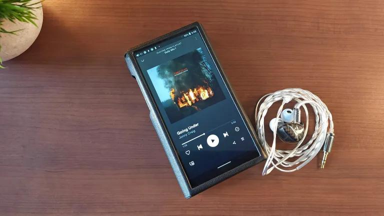 The FiiO M11 Plus DAP sitting on a desk with some IEMs