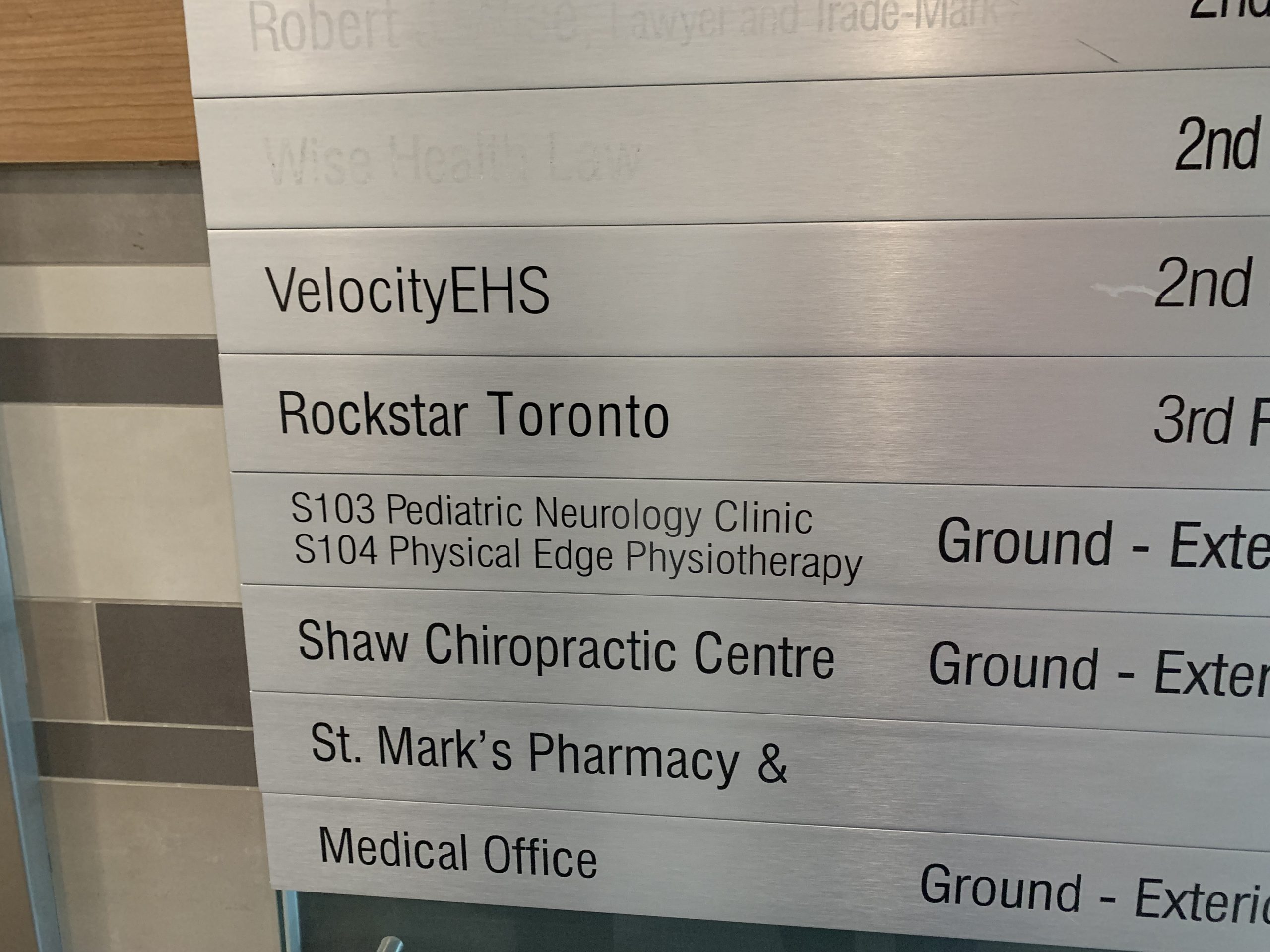 A metallic directory sign lists Rockstar Toronto on the 3rd floor, with additional listings like S103 Pediatric Neurology Clinic and S104 Physical Edge Physiotherapy on the ground floor.