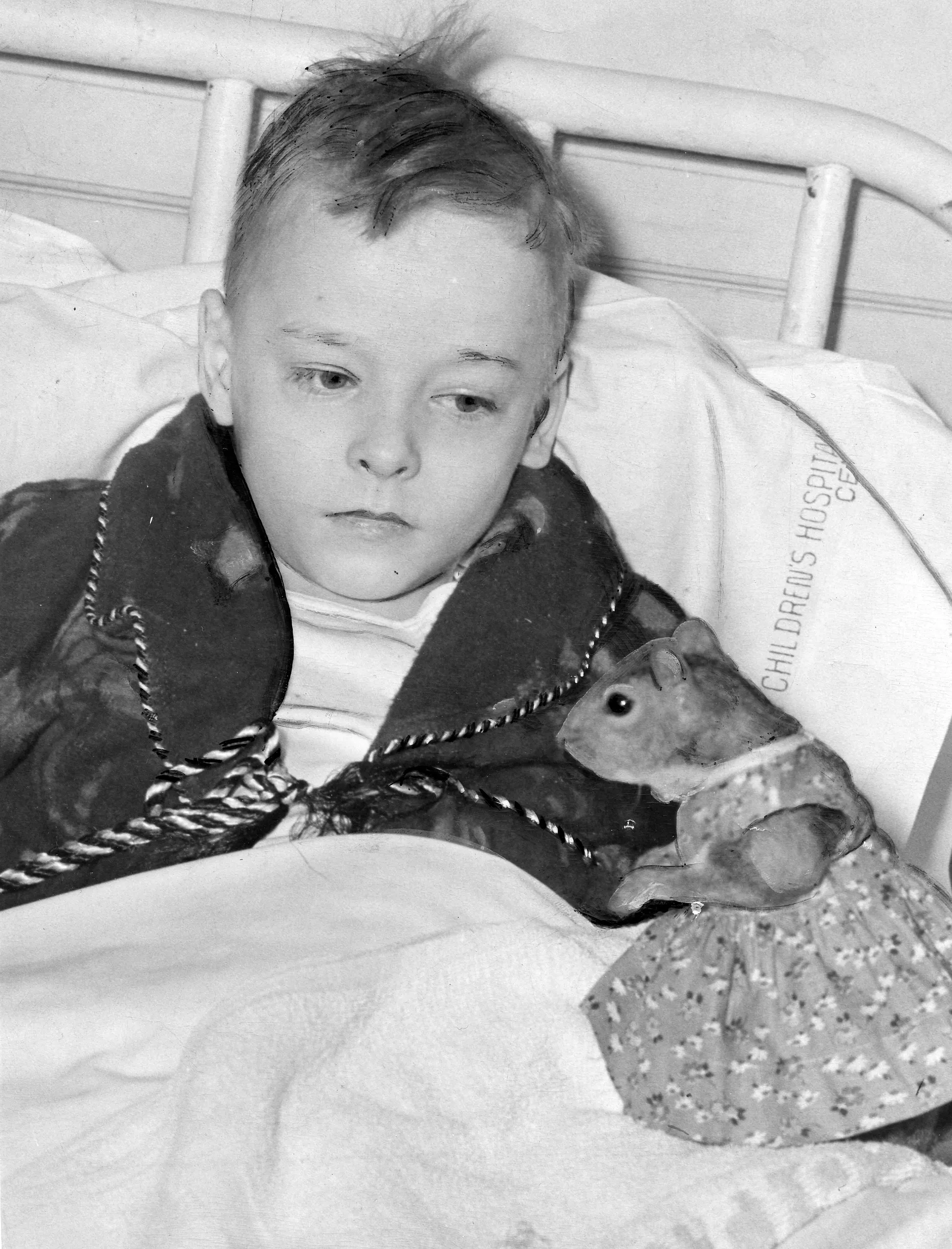 Κατά τη διάρκεια του Β' Παγκοσμίου Πολέμου, ένας σκίουρος που φορούσε φόρεμα πούλησε πολεμικά ομόλογα μαζί με το FDR Μια ασπρόμαυρη ιστορική φωτογραφία ενός νεαρού αγοριού σε κρεβάτι νοσοκομείου στο Παιδιατρικό Κέντρο στην Ουάσιγκτον, DC Το αγόρι, φορώντας μια σκούρα ρόμπα με σχέδια, κοιτάζει τον Tommy Tucker, έναν κατοικίδιο σκίουρο ντυμένο με φόρεμα με λουλουδάτο στάμπα. Ο σκίουρος είναι τοποθετημένος στα καλύμματα του κρεβατιού και το όνομα του νοσοκομείου φαίνεται μερικώς στη λευκή μαξιλαροθήκη πίσω από το αγόρι.