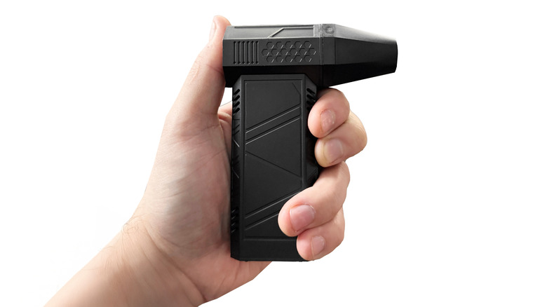 Ένα χέρι που κρατά ένα ηλεκτρονικό ξεσκονόπανο πεπιεσμένου αέρα.