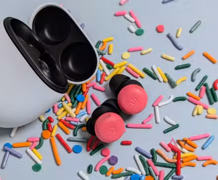 Ανοιχτή θήκη Google Pixel Buds Pro 2 με μπουμπούκια παιώνιας στο τραπέζι που περιβάλλεται από ψεκασμούς