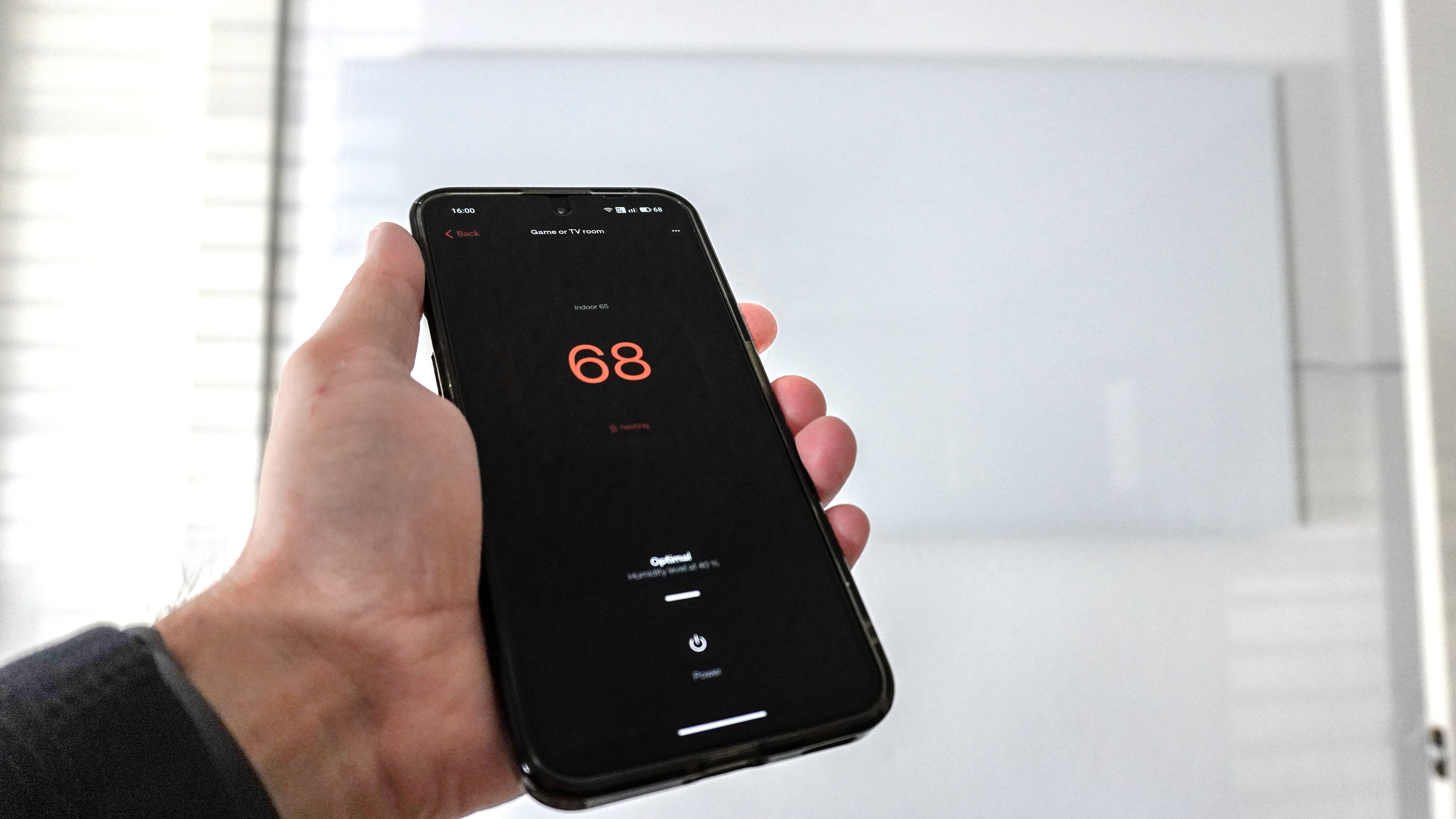 Ένα άτομο που χρησιμοποιεί την εφαρμογή Boldr για να ελέγξει την επιτοίχια, έξυπνη υπέρυθρη θερμάστρα Boldr Kelvin