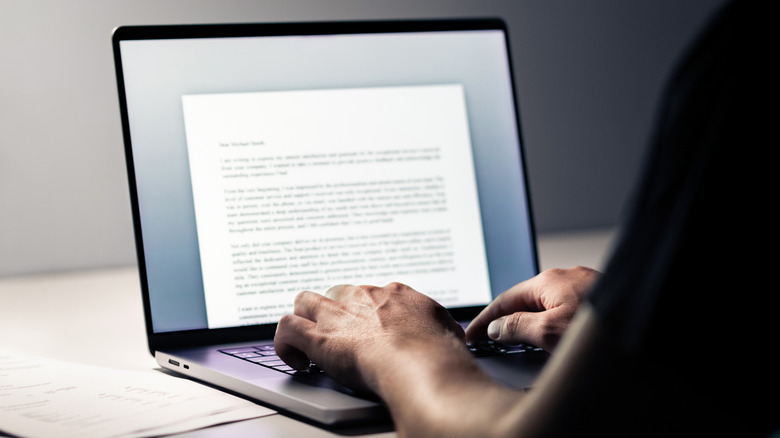 Άτομο που πληκτρολογεί και χρησιμοποιεί επεξεργαστή κειμένου σε φορητό υπολογιστή