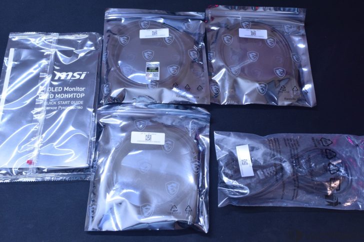 MSI OLED Monitor quick start guide and multiple labeled cables are packaged in sealed bags with MSI logo branding.