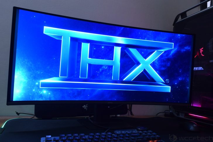 A curved MSI monitor displaying the large blue 'THX' logo on its screen, with a Razer logo visible on the monitor stand.