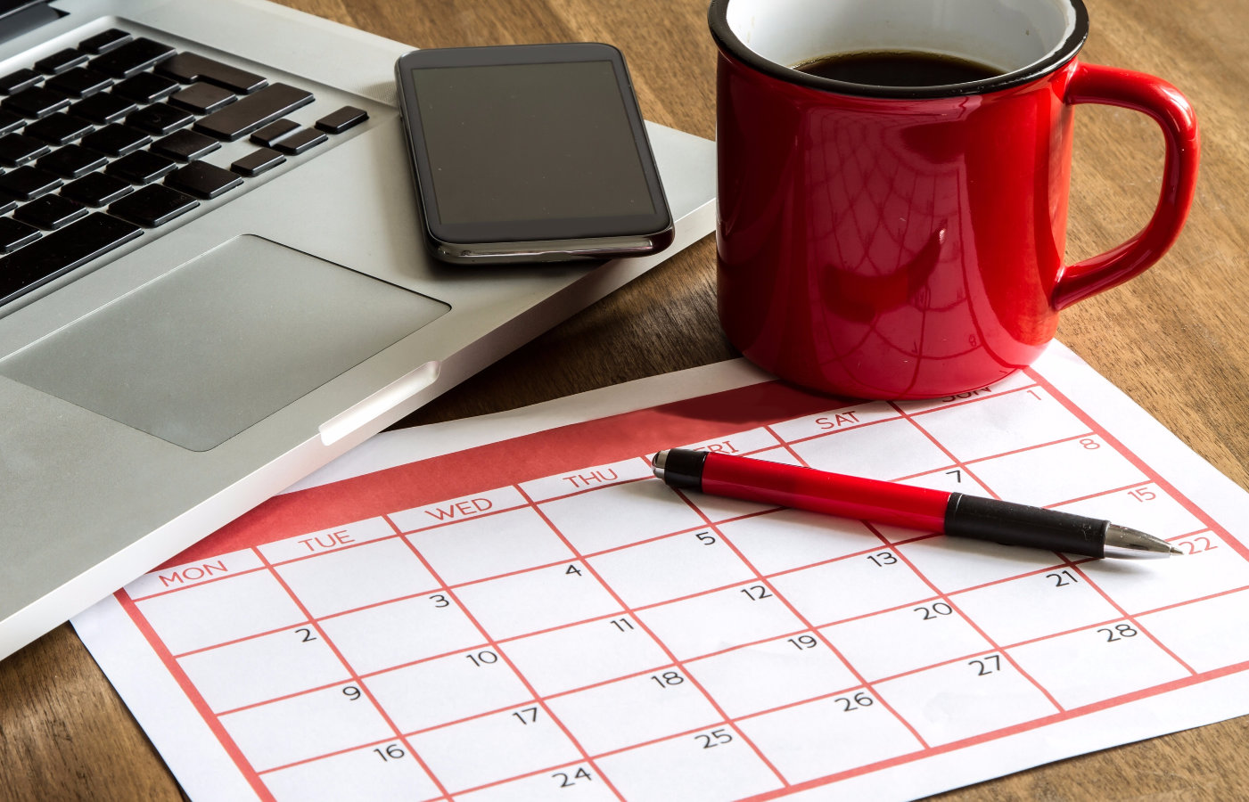 Ημερολόγιο δίπλα σε φορητό υπολογιστή και φλιτζάνι καφέ