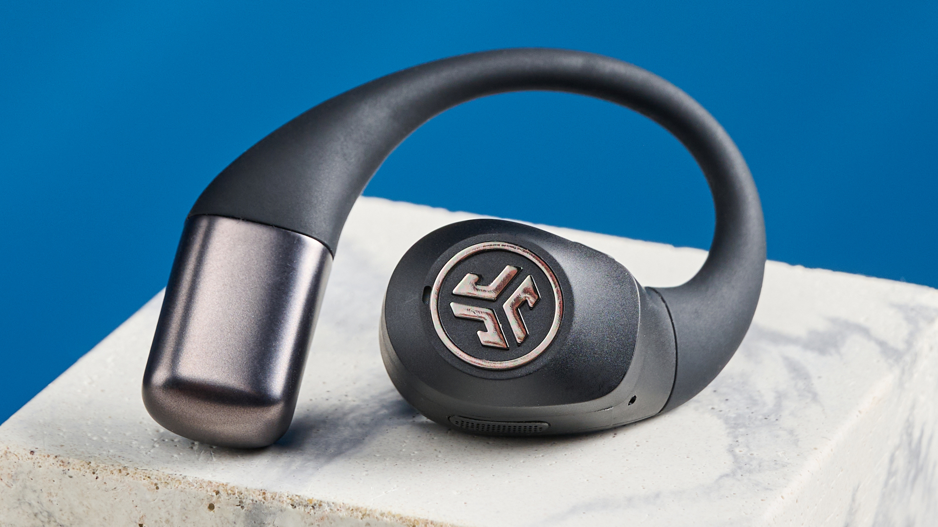 Jlab επικά ανοιχτά αθλητικά ανοιχτά ακουστικά σε μαύρο χρώμα που φωτογραφίζεται σε μπλε φόντο.