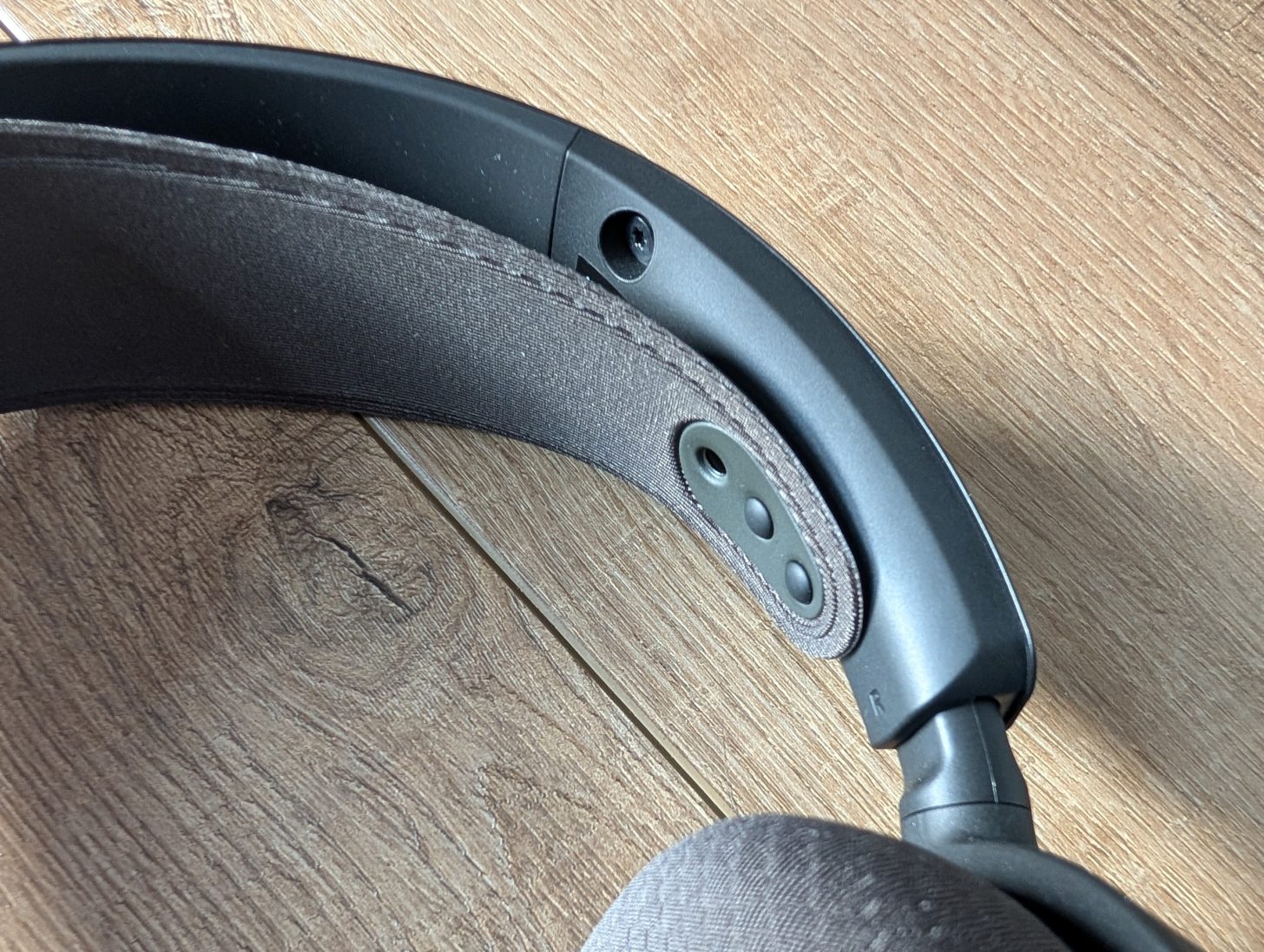 Κοντινό πλάνο ενός κεφαλόδεσμου χωρίς επώνυμο που στηρίζεται σε μια ξύλινη επιφάνεια, που δείχνει τις λεπτομέρειες της άρθρωσης και της επένδυσης.