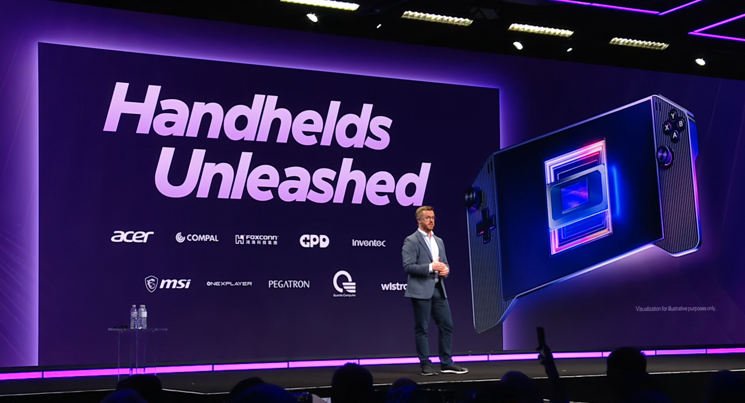 A presenter stands on stage next to a large display with the text 'Handhelds Unleashed' and logos of brands including Acer, MSI, and Foxconn, alongside an illustration of a handheld gaming device.