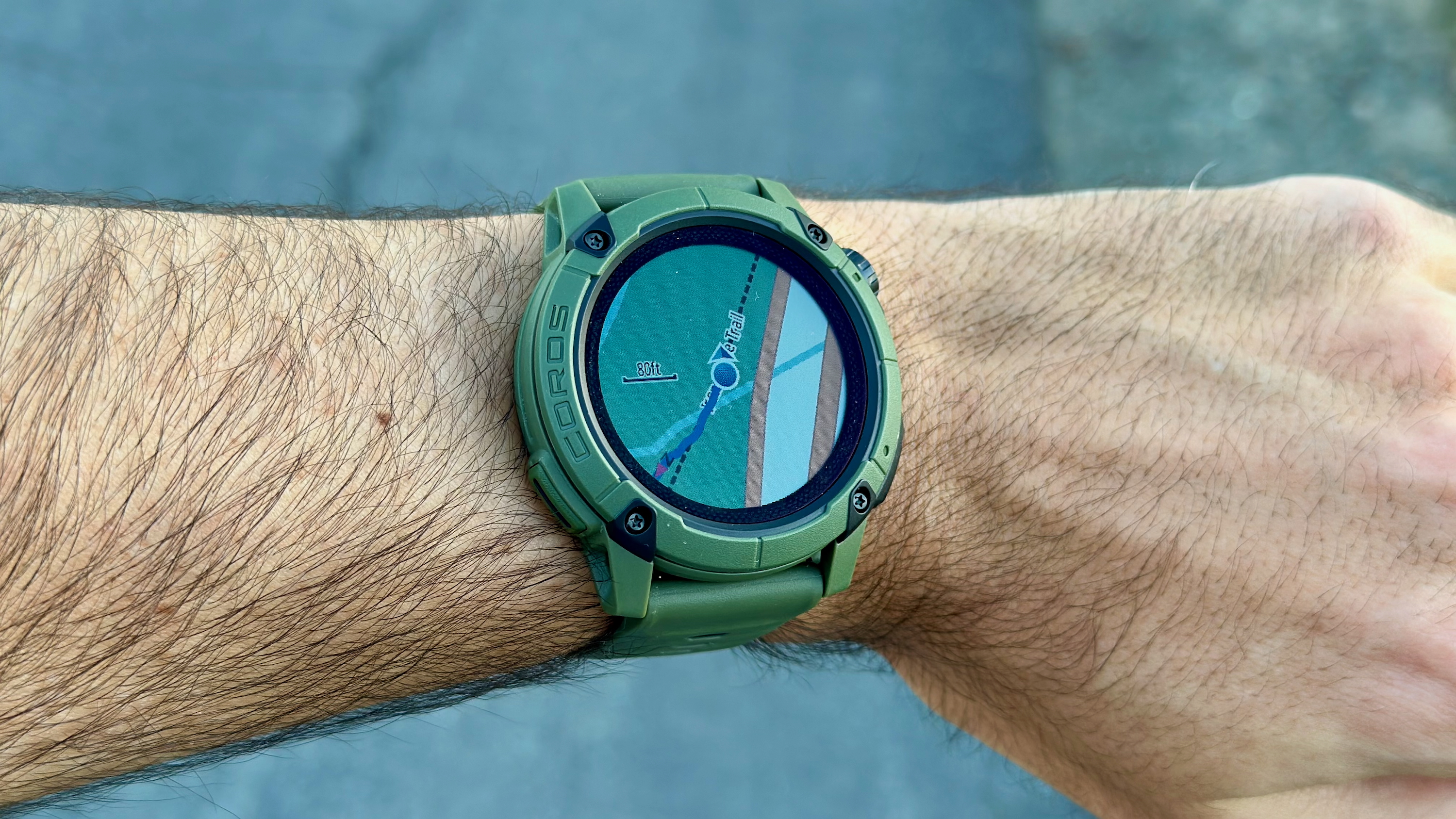 The COROS NOMAD watch on a wrist showing the wearer's current map location on a trail.