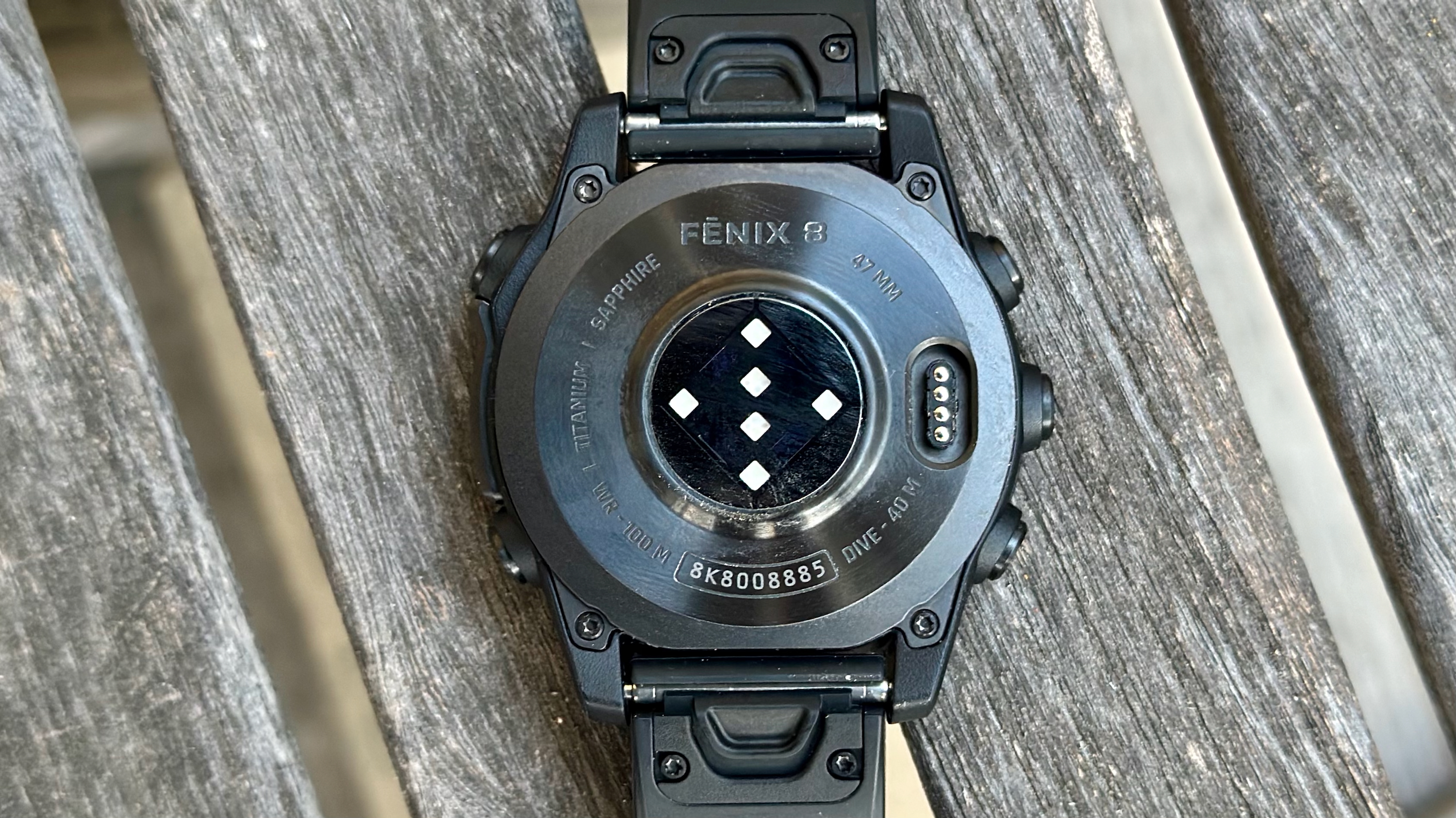 Το κάτω μέρος του τιτανίου Garmin Fenix ​​8, που δείχνει τη θύρα φόρτισης, τις υποδοχές μπάντας ρολογιού QuickFit και τις χαραγμένες πληροφορίες για το ρολόι