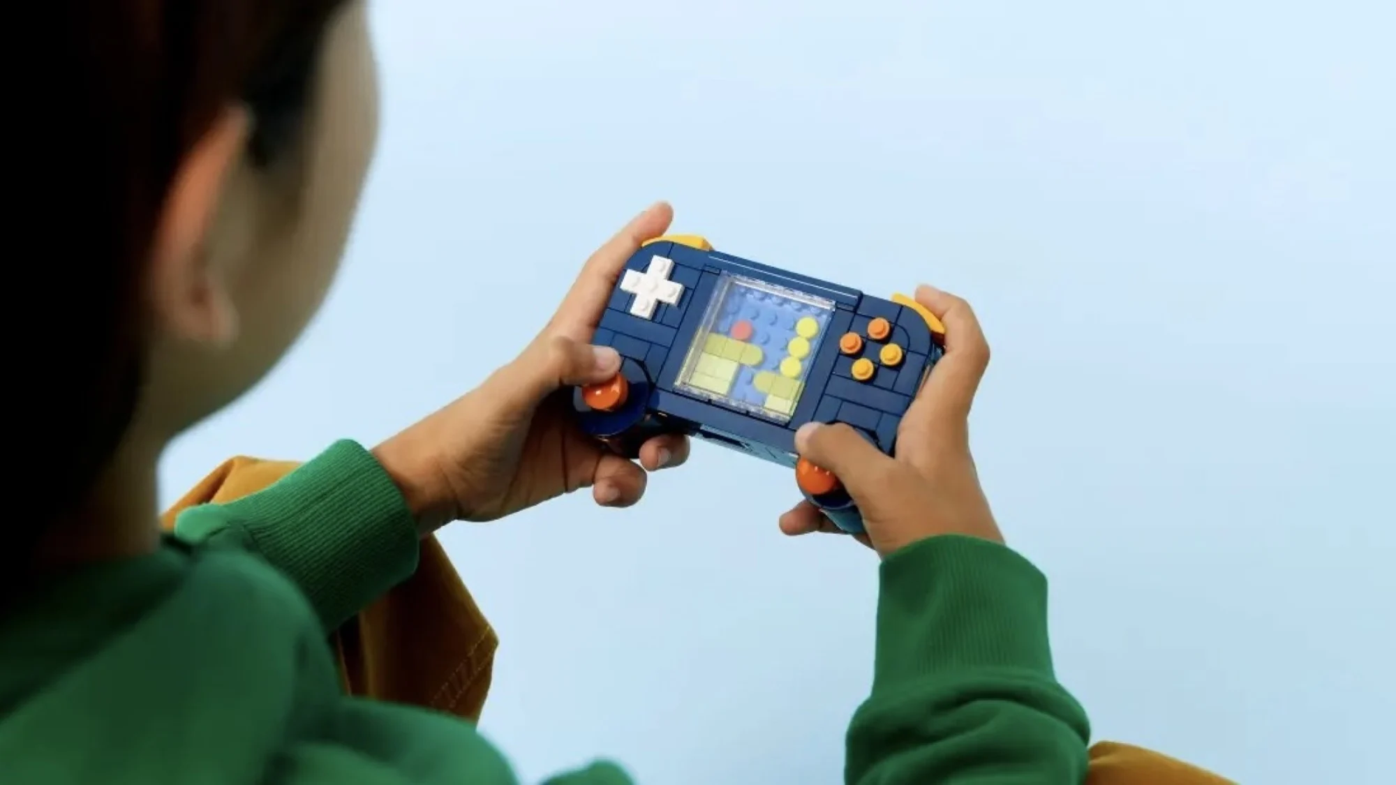 person playing lego retro gaming console in blue room