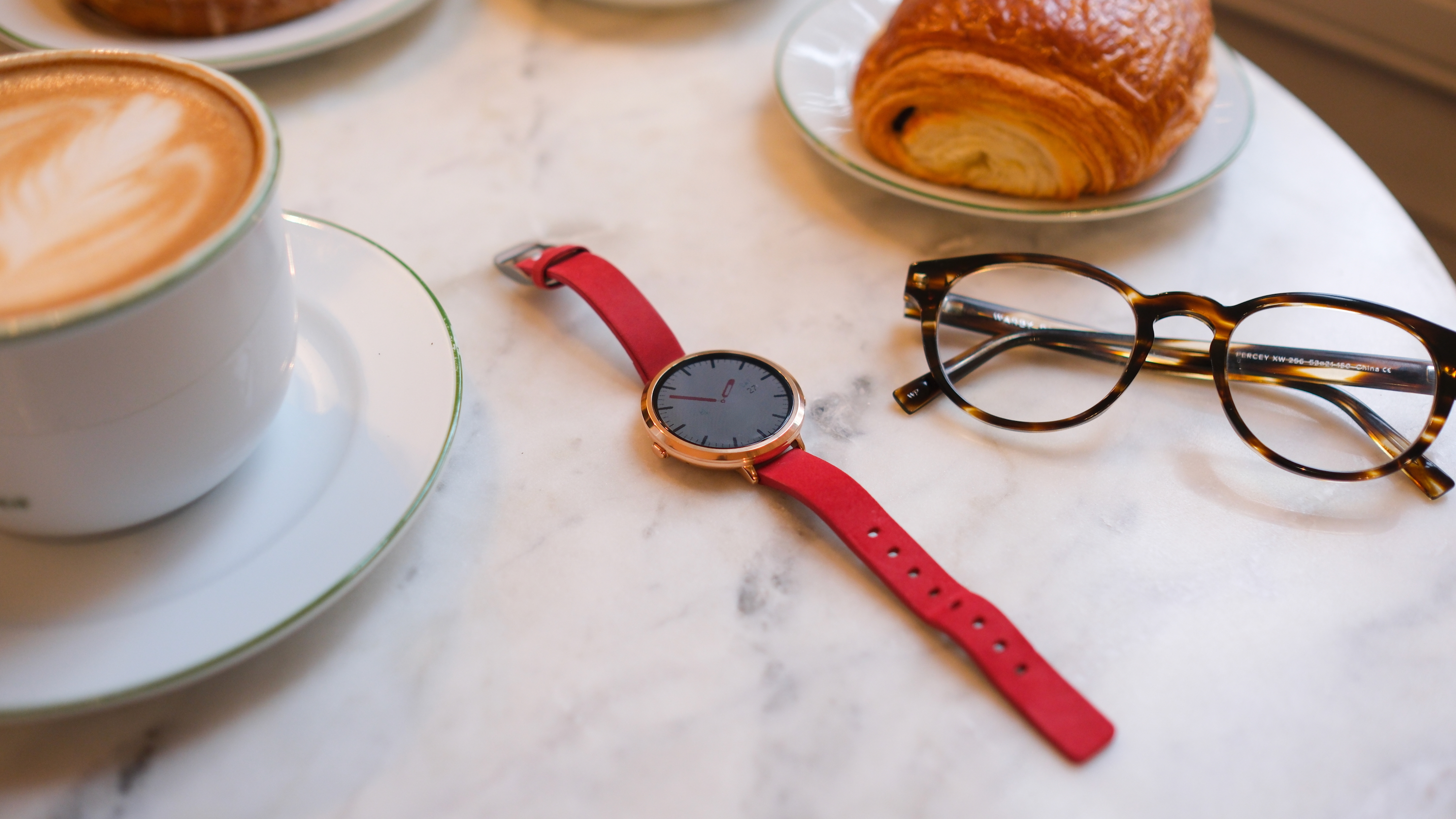 Το Pebble Round 2 προσφέρει κομψή, απογυμνωμένη εναλλακτική του Time 2 Φωτογραφία του Pebble Round 2 που κάθεται σε έναν μαρμάρινο πάγκο που περιβάλλεται από στηρίγματα.