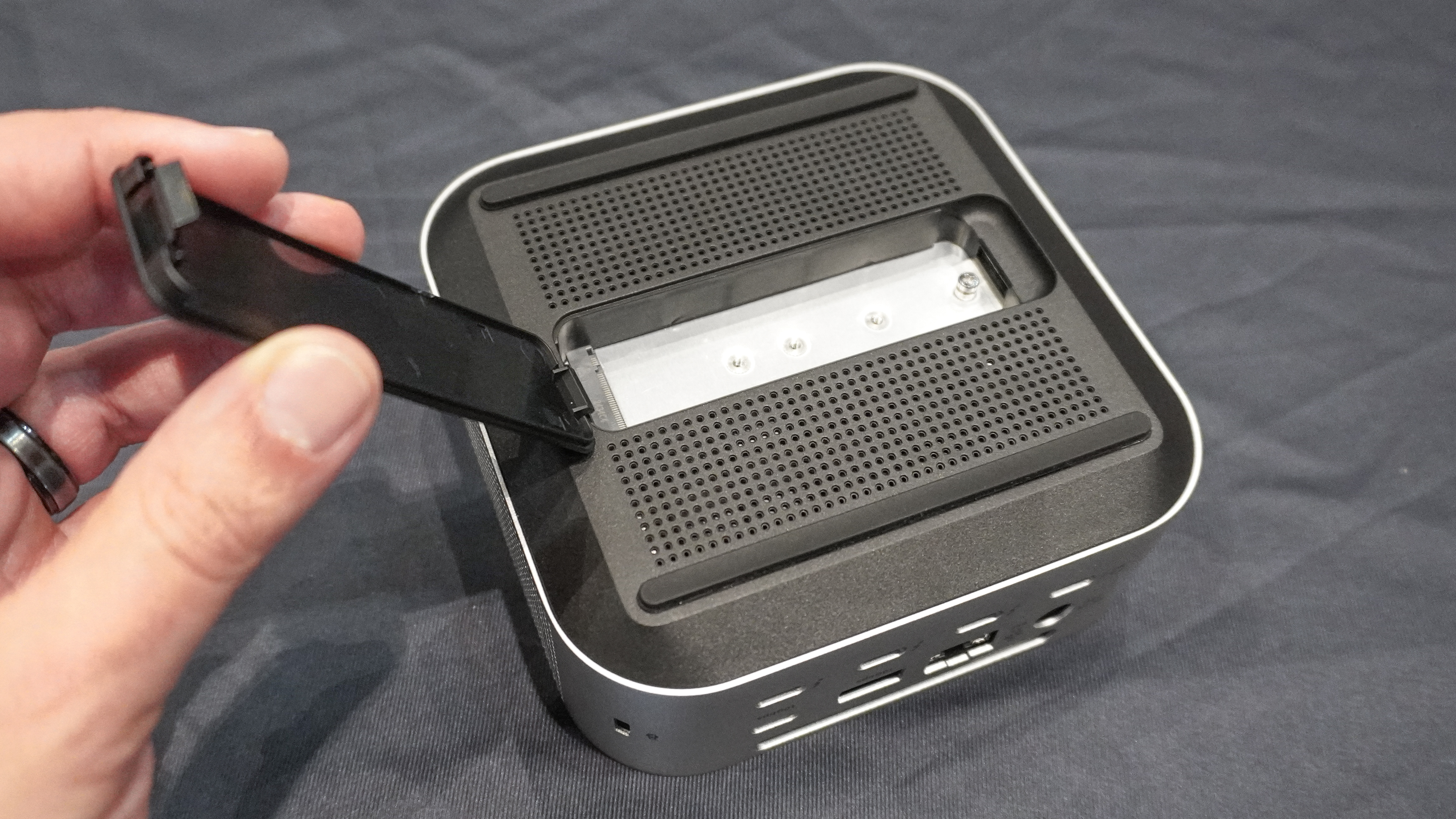 Ένα άτομο που ανοίγει το καπάκι του περιβλήματος SSD στο κάτω μέρος του Satechi CubeDock
