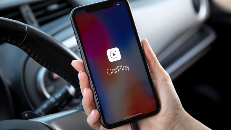 Ένα άτομο που κρατά ένα iPhone με το εικονίδιο Apple CarPlay στην οθόνη