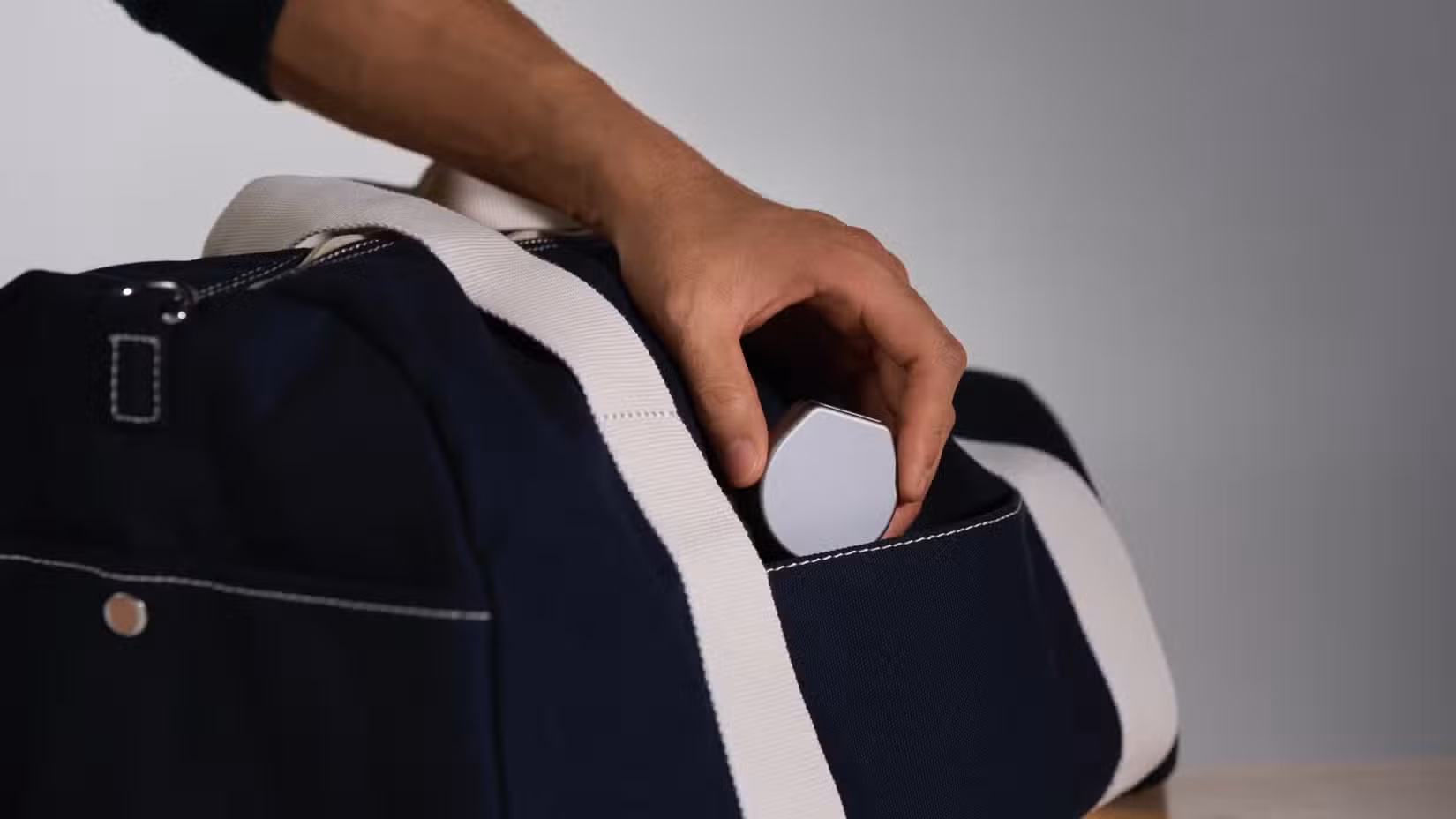 Ένα άτομο που βάζει τη θήκη φόρτισης Oura σε μια τσάντα