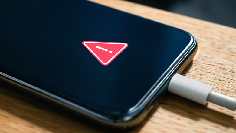 Ένα τηλέφωνο που κάθεται σε ένα τραπέζι, συνδεδεμένο, με ένα προειδοποιητικό λογότυπο στην οθόνη