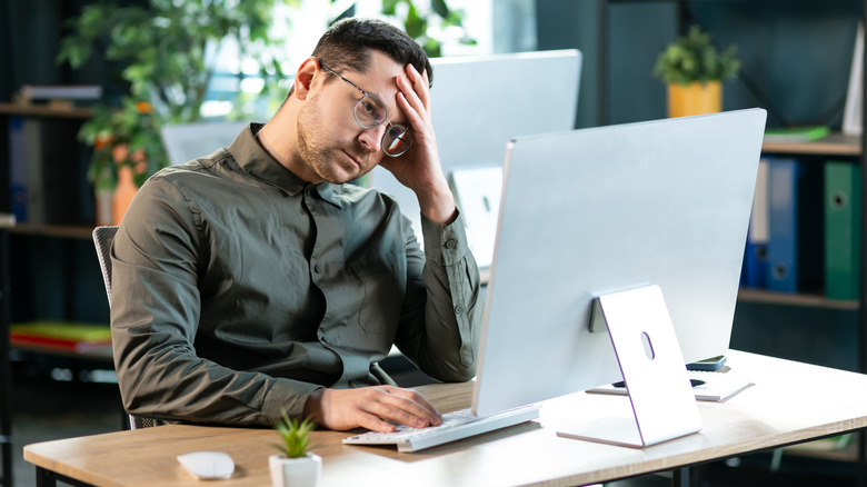 Ένας υπάλληλος γραφείου είναι απογοητευμένος στην οθόνη του υπολογιστή του