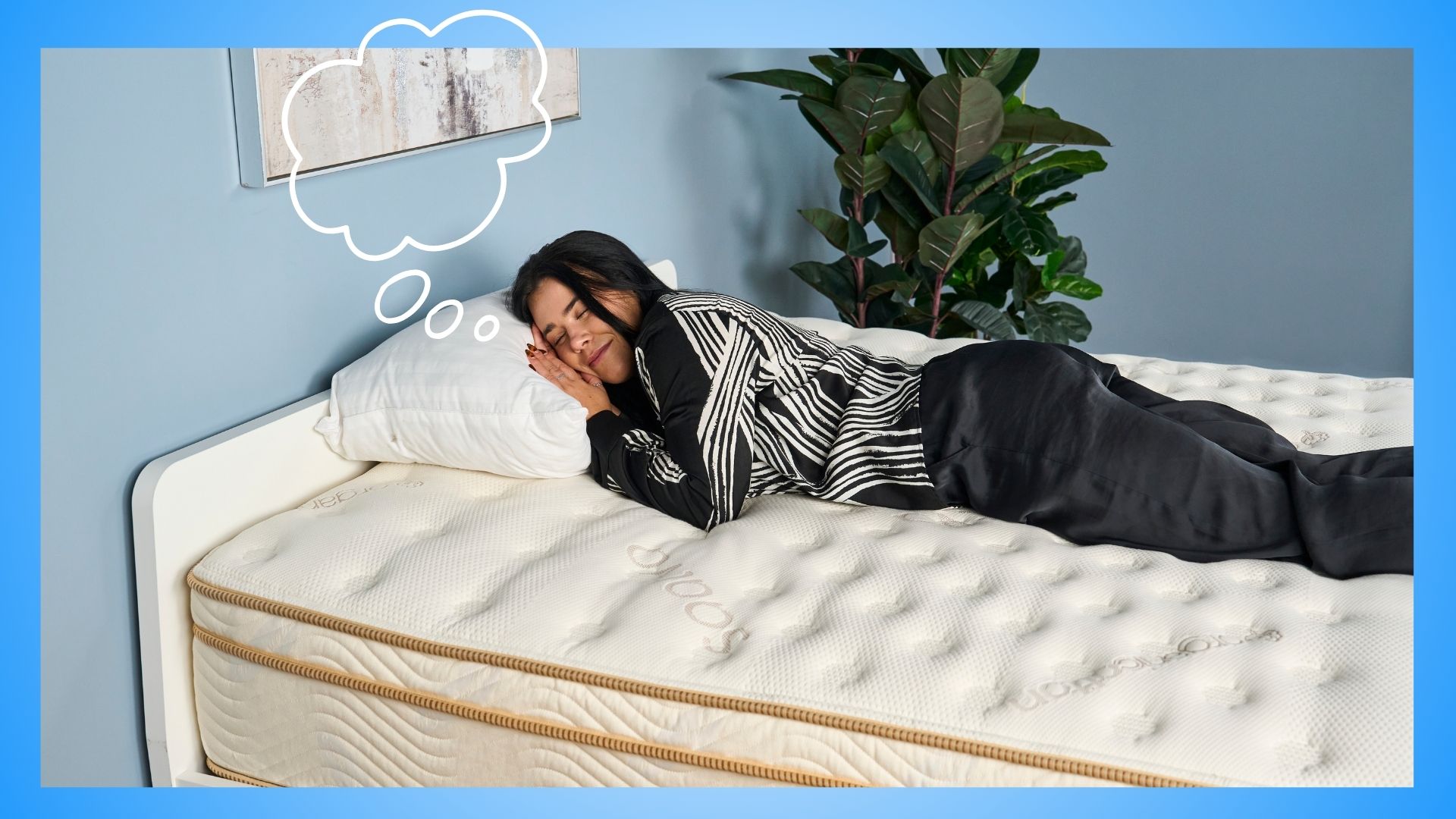 Μια γυναίκα με μαύρα μαλλιά φορώντας ασπρόμαυρες πιτζάμες κοιμάται στο στρώμα Saatva Solaire στο στούντιο ύπνου με μια φυσαλίδα σκέψης