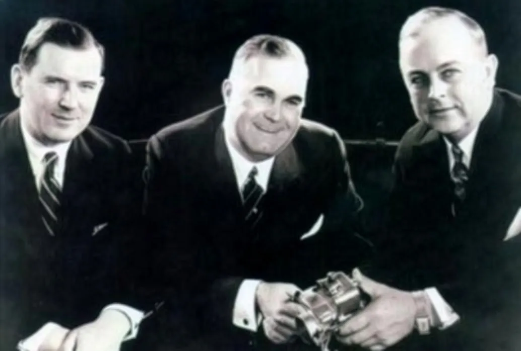 Black and white image of three middle aged white men in suits.