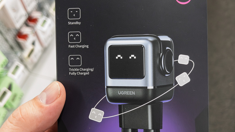 Ένα χέρι που κρατά έναν φορτιστή Ugreen στο κουτί του σε ένα κατάστημα