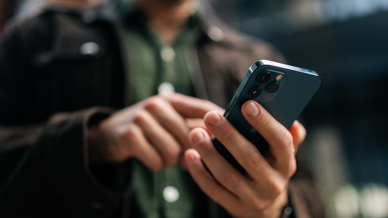 Ένα άτομο που κρατά ένα iPhone και αγγίζει την οθόνη του