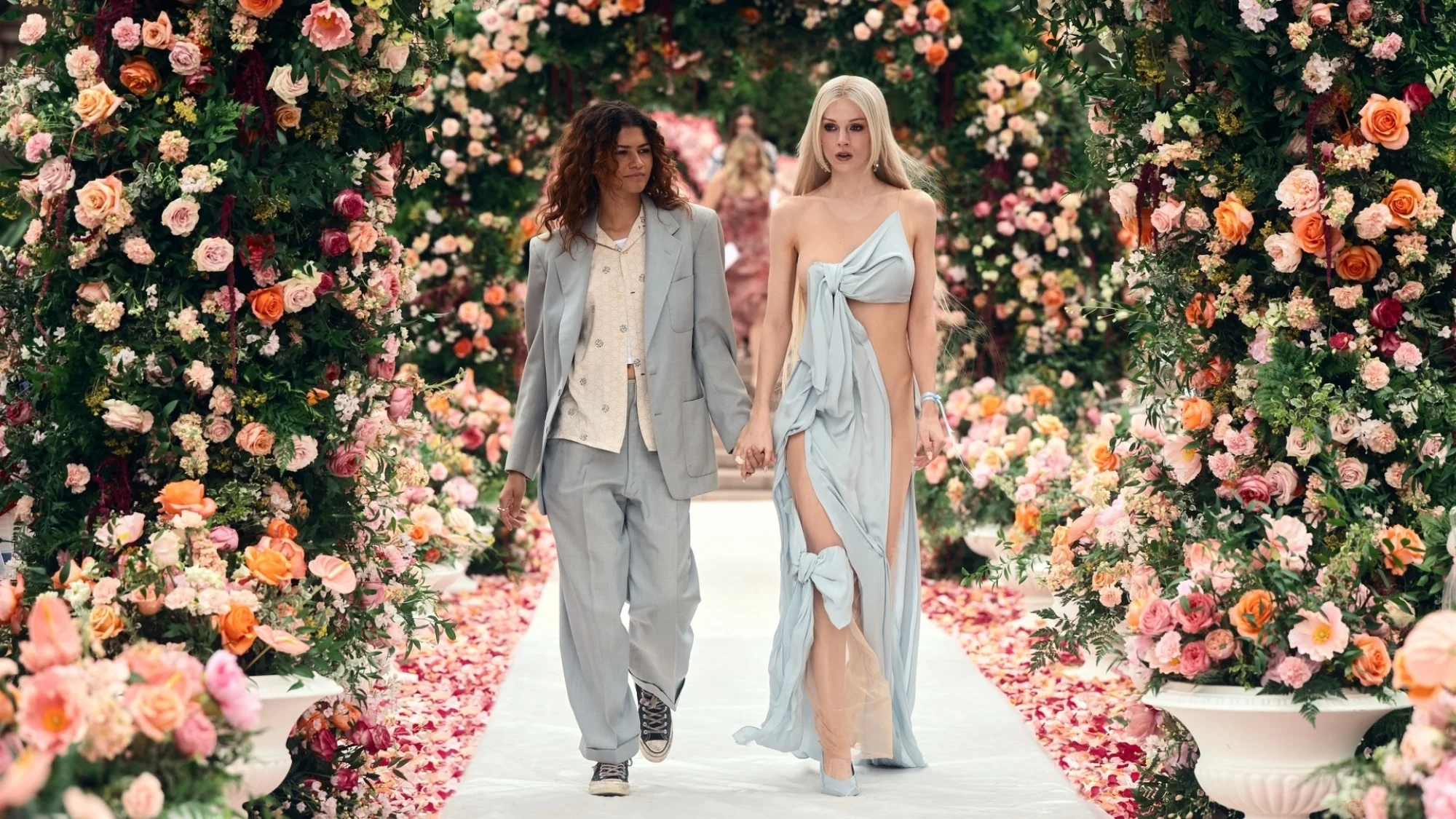 Δύο χαρακτήρες περπατούν σε ένα διάδρομο με τριαντάφυλλα.