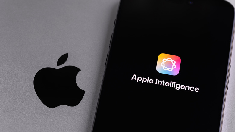 Ένα iPhone που εμφανίζει το λογότυπο Apple Intelligence βρίσκεται πάνω από ένα ασημί MacBook