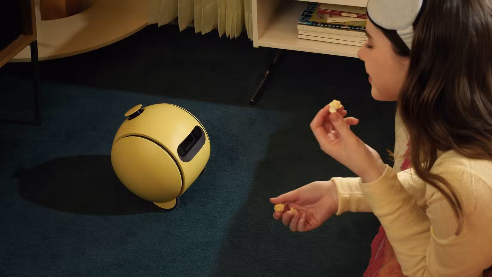 Μια εικόνα του Samsung Ballie στο πάτωμα που κοιτάζει ένα άτομο.