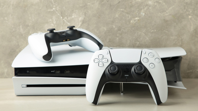 Κονσόλα PlayStation 5 με δύο χειριστήρια DualSense μπροστά.