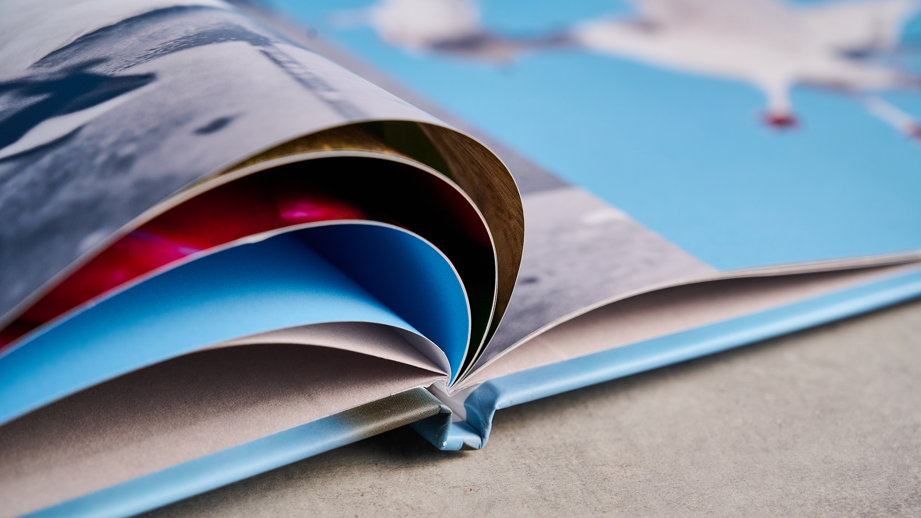 Το άλμπουμ φωτογραφιών θαμπώματος φωτογραφίζεται σε ένα τραπέζι μπροστά σε μπλε φόντο